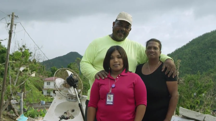 Three people standing with damaged Puerto Rico in the background