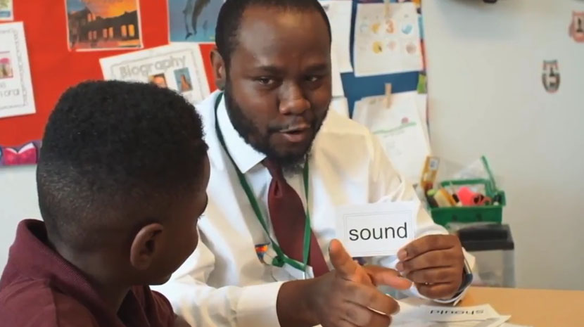 Doctor in lab coat working with a child and holding a card that says Sound